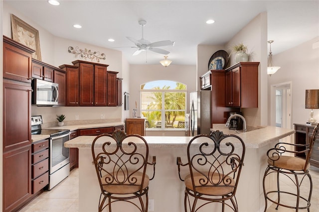 kitchen with a peninsula, light tile patterned flooring, stainless steel appliances, a kitchen bar, and recessed lighting