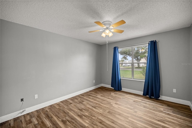 empty room featuring a ceiling fan, a textured ceiling, baseboards, and wood finished floors