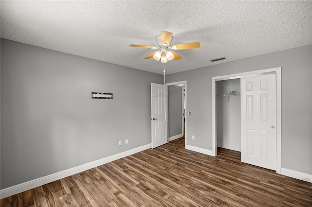 unfurnished bedroom with a closet, wood finished floors, visible vents, and baseboards