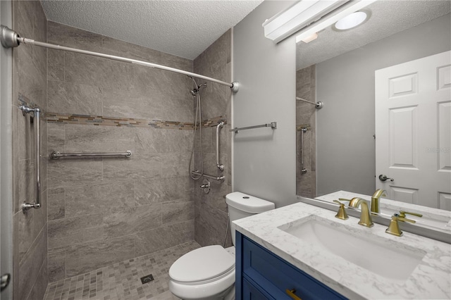 full bathroom featuring tiled shower, vanity, toilet, and a textured ceiling