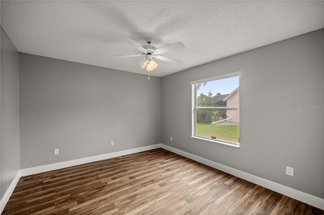 empty room featuring a textured ceiling, wood finished floors, a ceiling fan, and baseboards