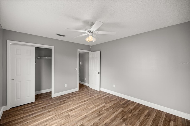 unfurnished bedroom featuring baseboards, visible vents, wood finished floors, a textured ceiling, and a closet