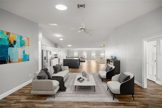 living room featuring visible vents, vaulted ceiling, a ceiling fan, and wood finished floors