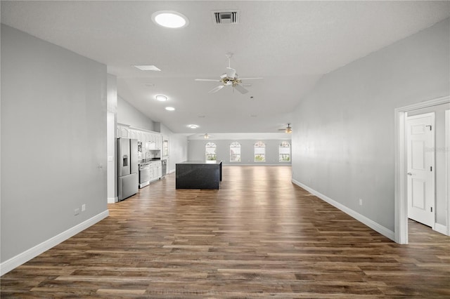 unfurnished living room featuring dark wood-style floors, ceiling fan, visible vents, and vaulted ceiling