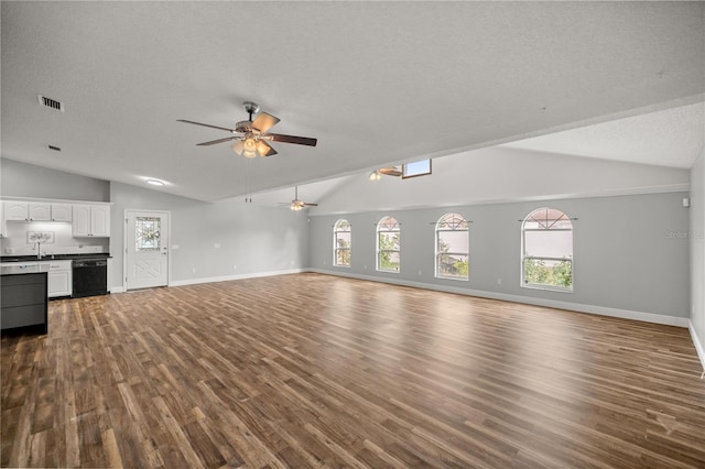 unfurnished living room with visible vents, a ceiling fan, dark wood-type flooring, vaulted ceiling, and a textured ceiling