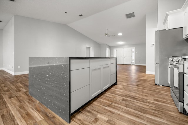 kitchen with light wood-type flooring, stainless steel range oven, visible vents, and white cabinets