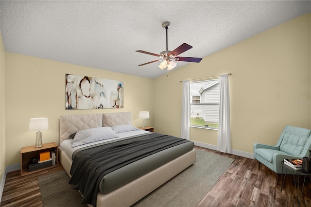 bedroom with a textured ceiling, wood finished floors, a ceiling fan, baseboards, and vaulted ceiling