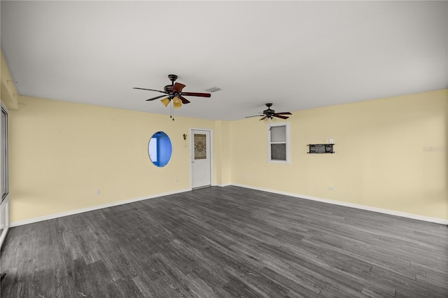 spare room featuring ceiling fan, baseboards, visible vents, and dark wood finished floors