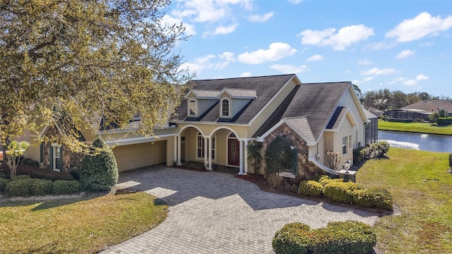 view of front facade featuring a garage, decorative driveway, a front yard, and stucco siding