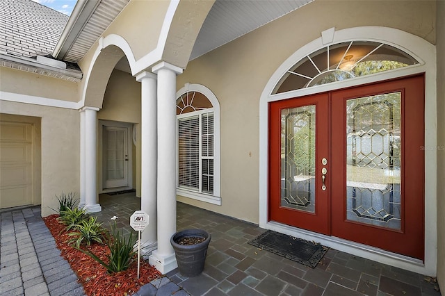 entrance to property featuring stucco siding, a shingled roof, and french doors