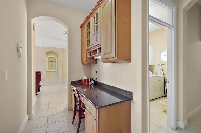 hallway featuring arched walkways, visible vents, washer and clothes dryer, and baseboards