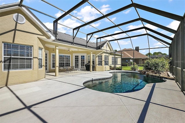 outdoor pool featuring glass enclosure, a patio area, and ceiling fan