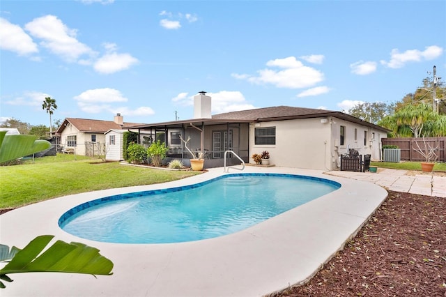 view of pool featuring a fenced in pool, an outbuilding, a yard, a sunroom, and fence