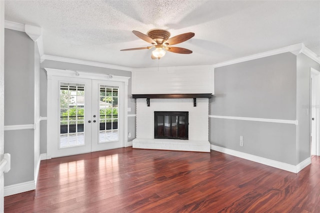 unfurnished living room featuring french doors, crown molding, a brick fireplace, a textured ceiling, and wood finished floors