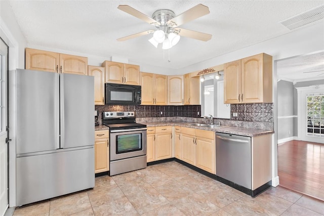 kitchen with appliances with stainless steel finishes, light brown cabinets, and visible vents