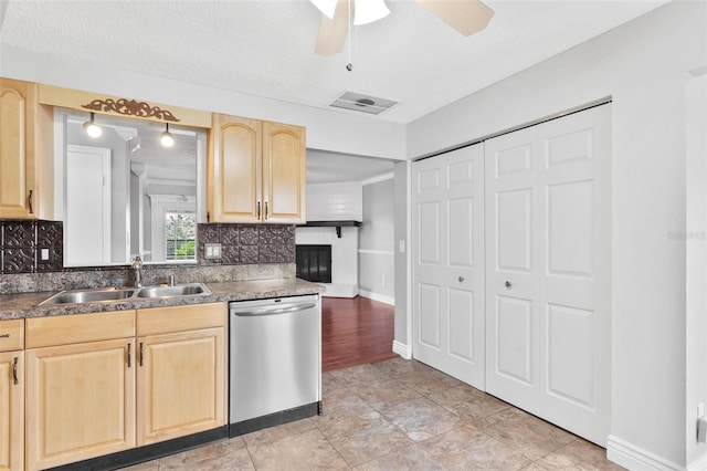 kitchen with visible vents, decorative backsplash, stainless steel dishwasher, light brown cabinetry, and a sink