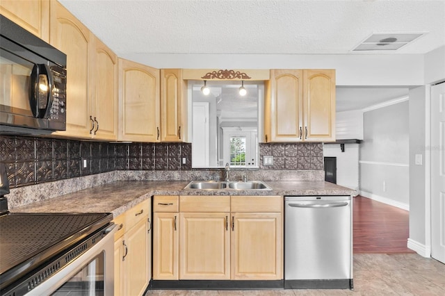 kitchen featuring visible vents, appliances with stainless steel finishes, a sink, light brown cabinets, and backsplash