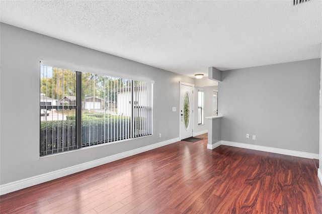 interior space with a textured ceiling, wood finished floors, and baseboards