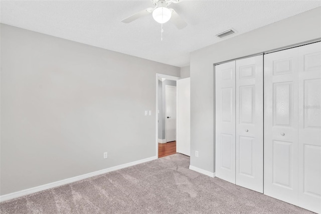 unfurnished bedroom with carpet floors, a closet, visible vents, a textured ceiling, and baseboards