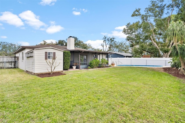 rear view of house featuring a fenced backyard, a chimney, a fenced in pool, and a yard