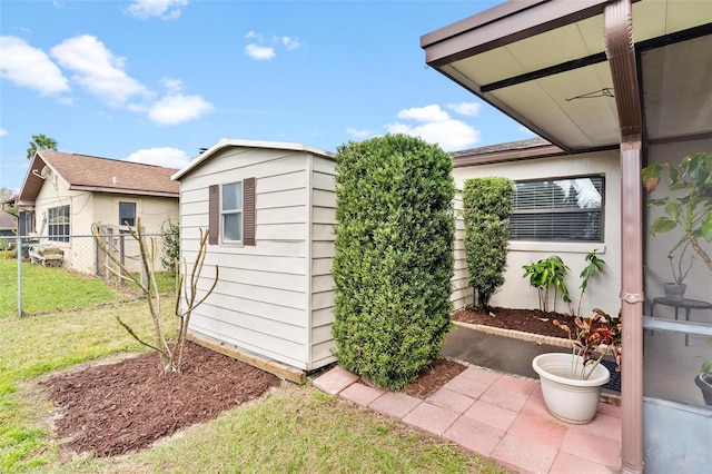 view of side of property with a yard, an outdoor structure, fence, and a storage unit