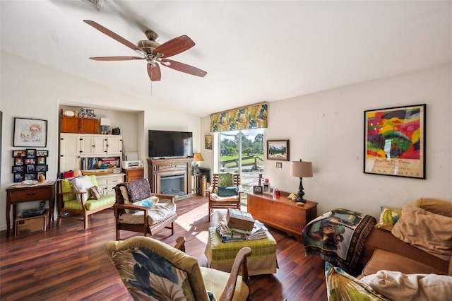 living room featuring lofted ceiling, ceiling fan, a glass covered fireplace, and dark wood finished floors