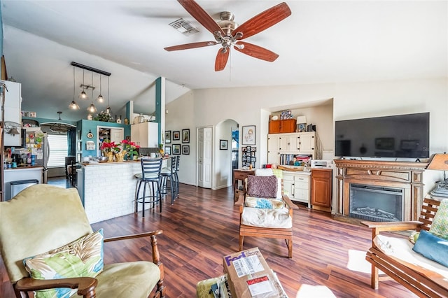 living area with arched walkways, visible vents, vaulted ceiling, and wood finished floors