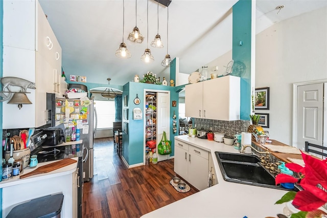 kitchen with dark wood-type flooring, a sink, vaulted ceiling, light countertops, and backsplash