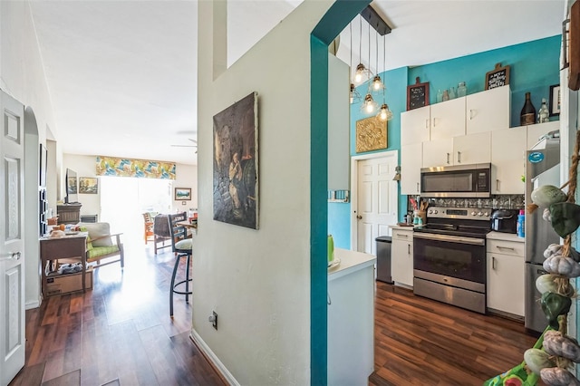 kitchen featuring white cabinetry, appliances with stainless steel finishes, light countertops, and dark wood-style flooring