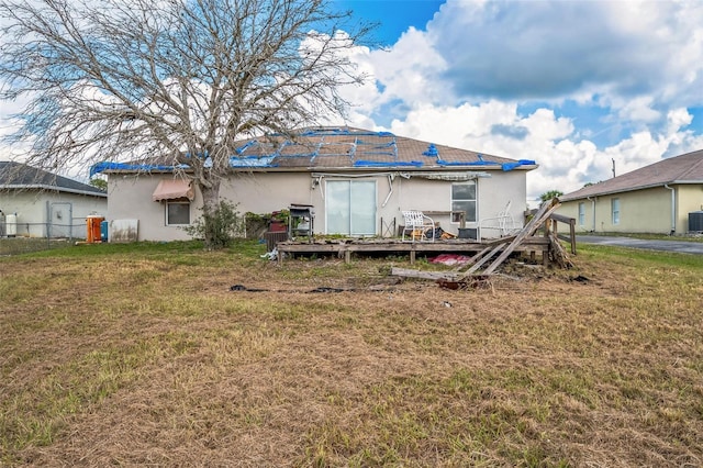 rear view of property with a yard, a deck, and stucco siding