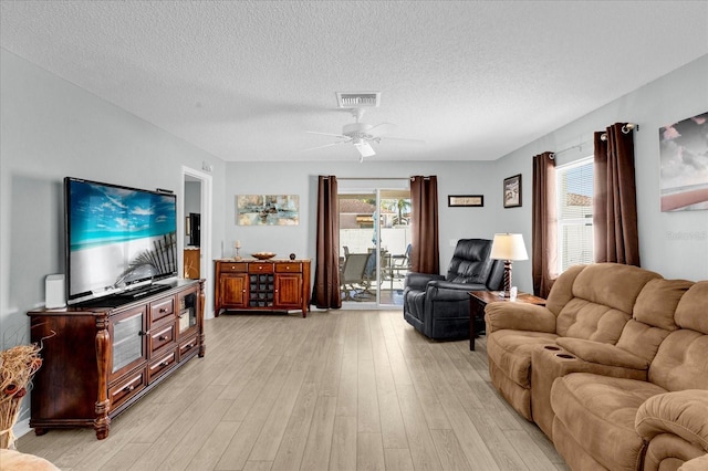 living room featuring visible vents, a healthy amount of sunlight, light wood-style flooring, and a textured ceiling