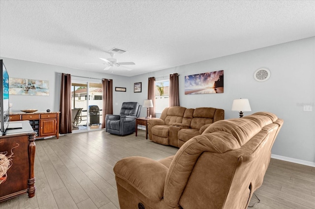 living room featuring light wood finished floors, plenty of natural light, and visible vents