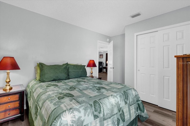 bedroom with a closet, visible vents, and wood finished floors