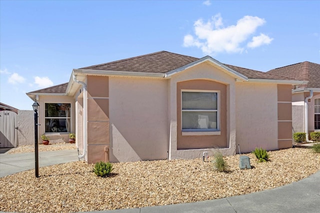 ranch-style home with stucco siding, a gate, and roof with shingles