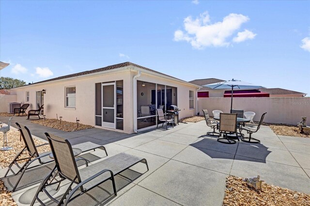 view of patio / terrace featuring a sunroom, a grill, fence, and outdoor dining area