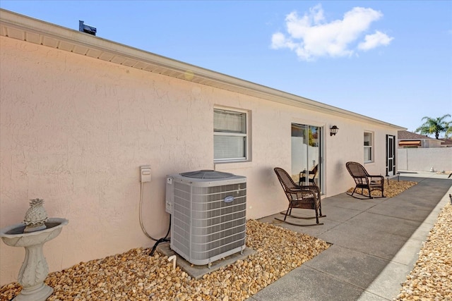 rear view of property with a patio, fence, central AC, and stucco siding