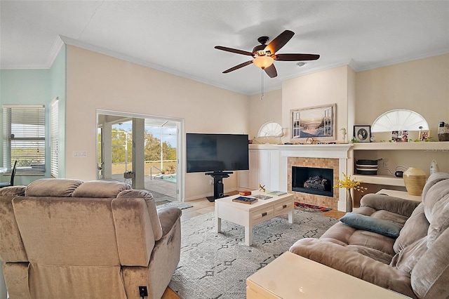 living area featuring baseboards, a fireplace, ornamental molding, and a ceiling fan