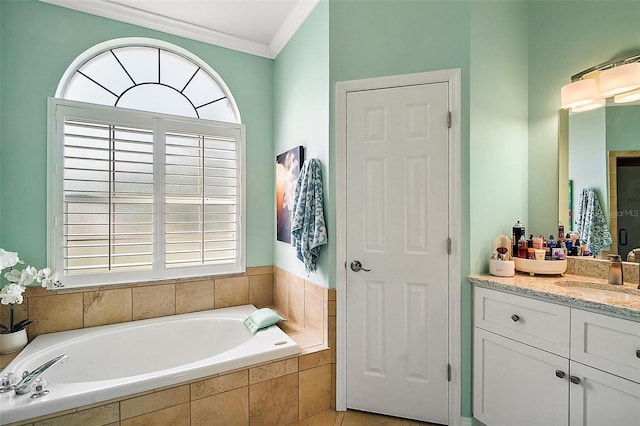 bathroom featuring ornamental molding, a healthy amount of sunlight, a garden tub, and vanity