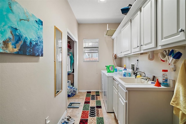 washroom with light tile patterned floors, a sink, baseboards, cabinet space, and washing machine and clothes dryer