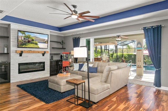 living area featuring visible vents, a large fireplace, ceiling fan, wood finished floors, and a sunroom