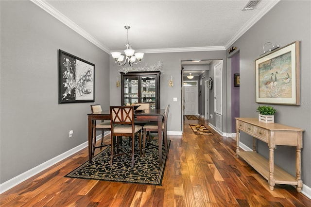 dining room featuring baseboards, wood finished floors, visible vents, and ornamental molding