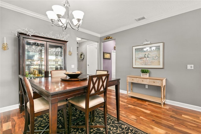 dining space with visible vents, wood finished floors, baseboards, and ornamental molding