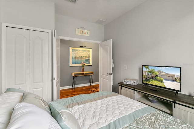 bedroom with wood finished floors, a closet, and baseboards