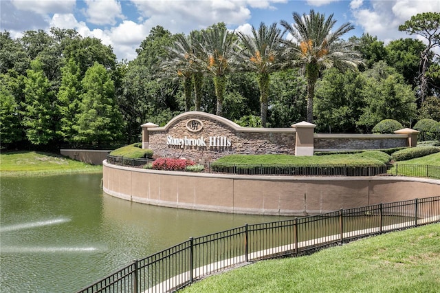 community / neighborhood sign featuring fence and a water view