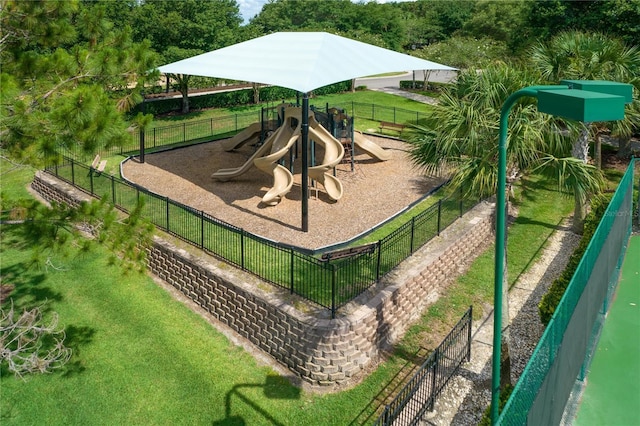 communal playground featuring a lawn and fence