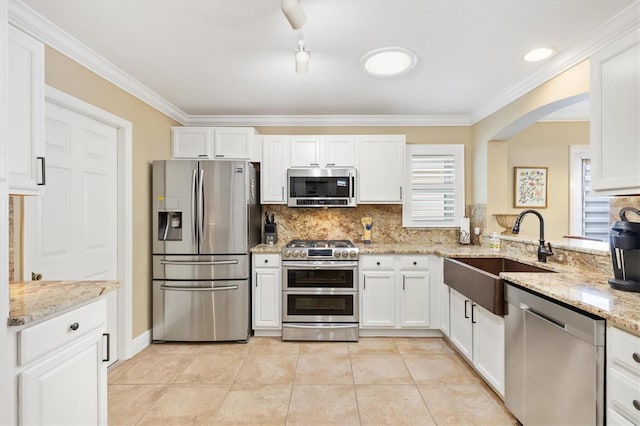 kitchen featuring tasteful backsplash, white cabinetry, stainless steel appliances, and a sink