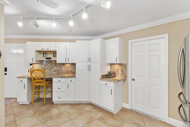 kitchen featuring ornamental molding, white cabinets, built in desk, and freestanding refrigerator