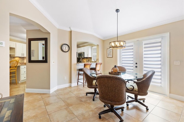 dining space with light tile patterned floors, ornamental molding, arched walkways, and baseboards