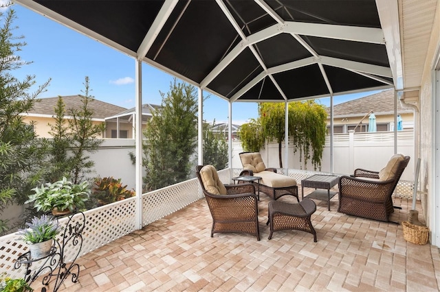 view of patio with glass enclosure, outdoor lounge area, and fence