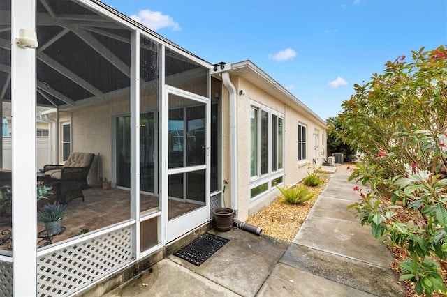 view of property exterior with glass enclosure, cooling unit, a patio, and stucco siding